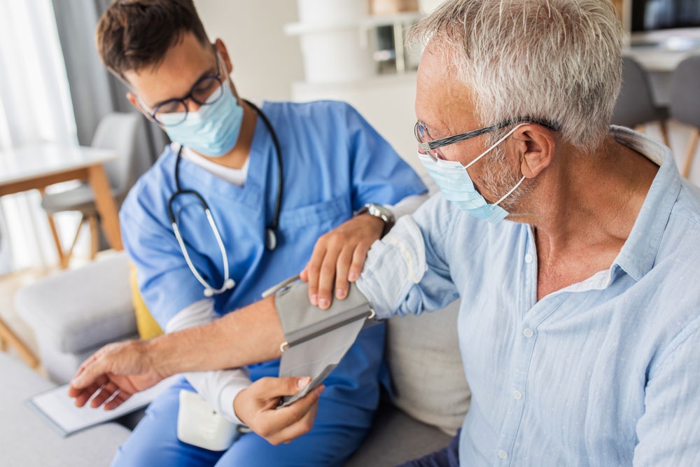 Doctor takes blood pressure of man wearing mask