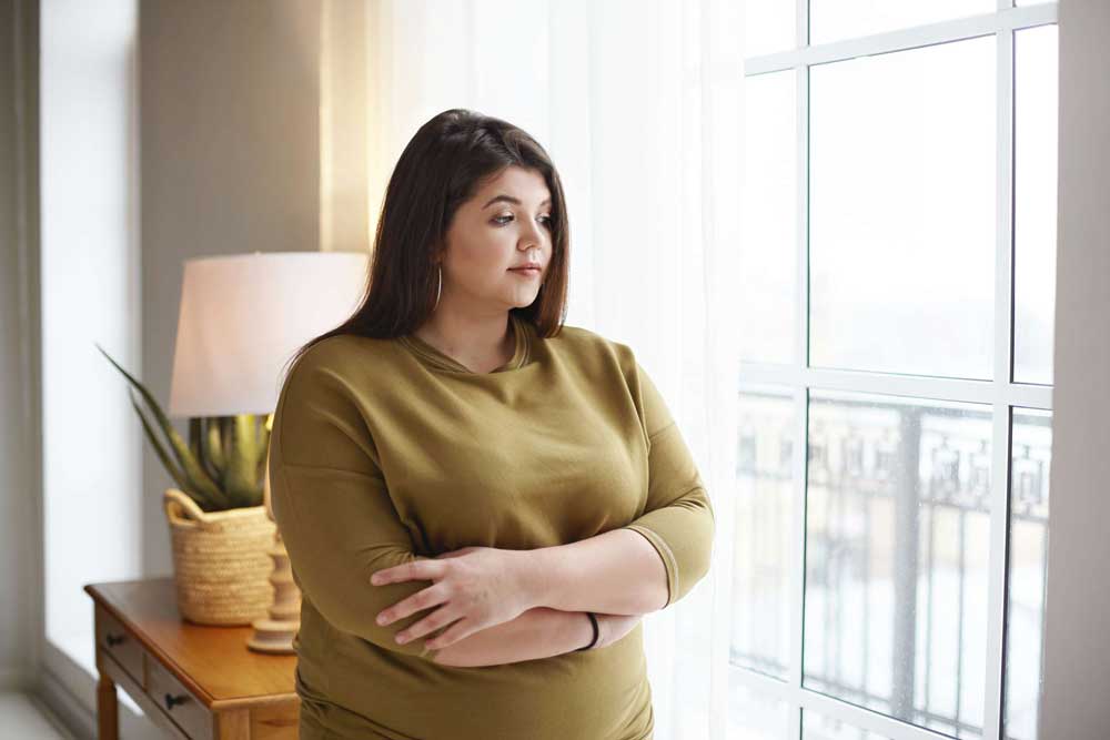 young woman holds stomach with sad expression